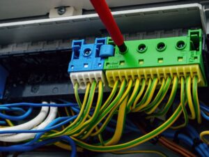 Caixa de distribuição elétrica com fios conectados a um dispositivo de aterramento, destacando a organização dos cabos.