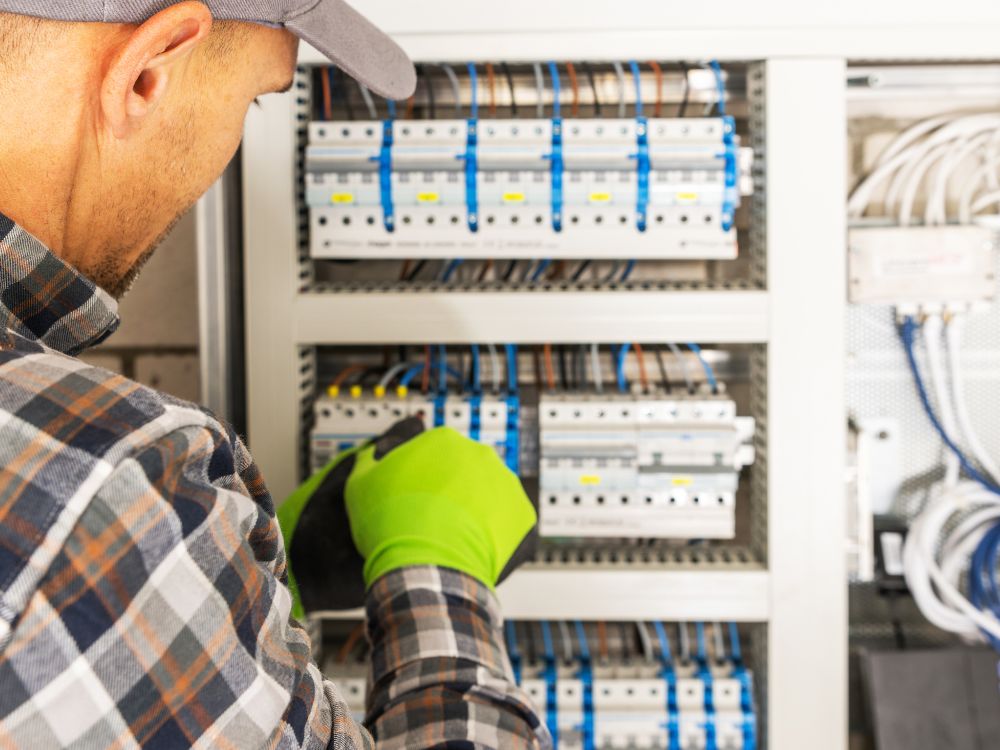 Eletricista analisando painel de distribuição com vários disjuntores, destacando a diferença entre disjuntor e fusível na manutenção.