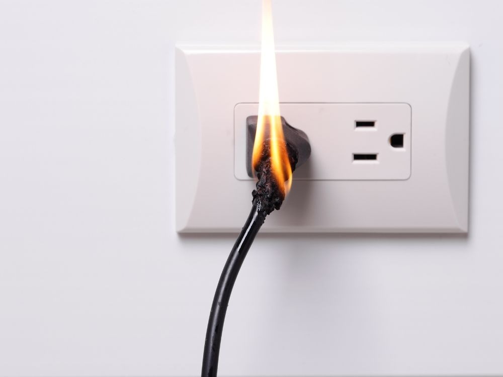 Cabo elétrico pegando fogo ao ser conectado na tomada, exemplificando claramente Como acontece o curto-circuito por aquecimento e isolamento danificado.