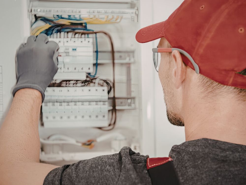 Eletricista realizando manutenção em quadro de energia com dr e disjuntor, ilustrando qual a diferença e a função de cada um.