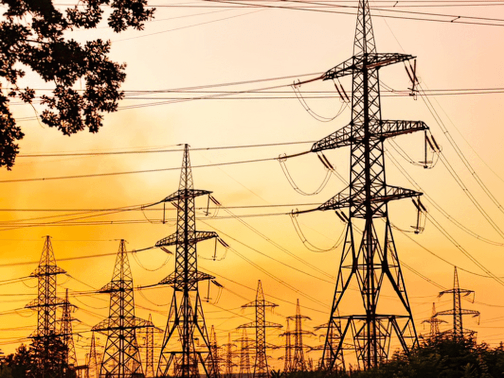 Torres e linhas de transmissão transportam energia elétrica em alta tensão entre diferentes regiões da rede elétrica.