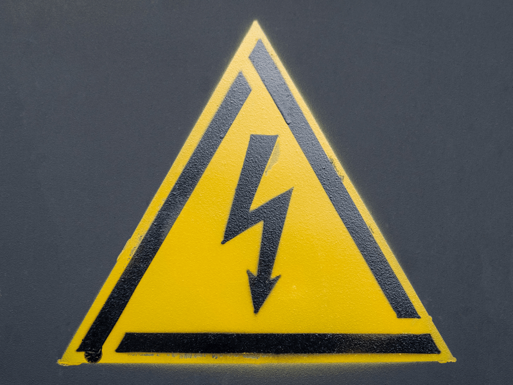 Símbolo amarelo de alerta com raio preto em destaque, indicando perigo de eletricidade e risco de choque elétrico.