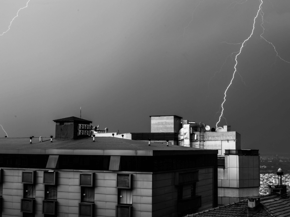 Descargas atmosféricas atingem o céu próximo a um edifício durante uma tempestade, destacando a importância da proteção contra raios.